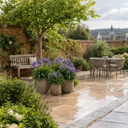 Agapanthe 'Pitchoune ® violet' (Agapanthus) — fleurs violettes en pots sur terrasse pavée · Photo d'illustration