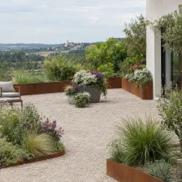 Euphorbe 'Starblast white' (Euphorbia) — grande terrasse gravillonnée avec massifs de plantes fleuries · Photo d'illustration